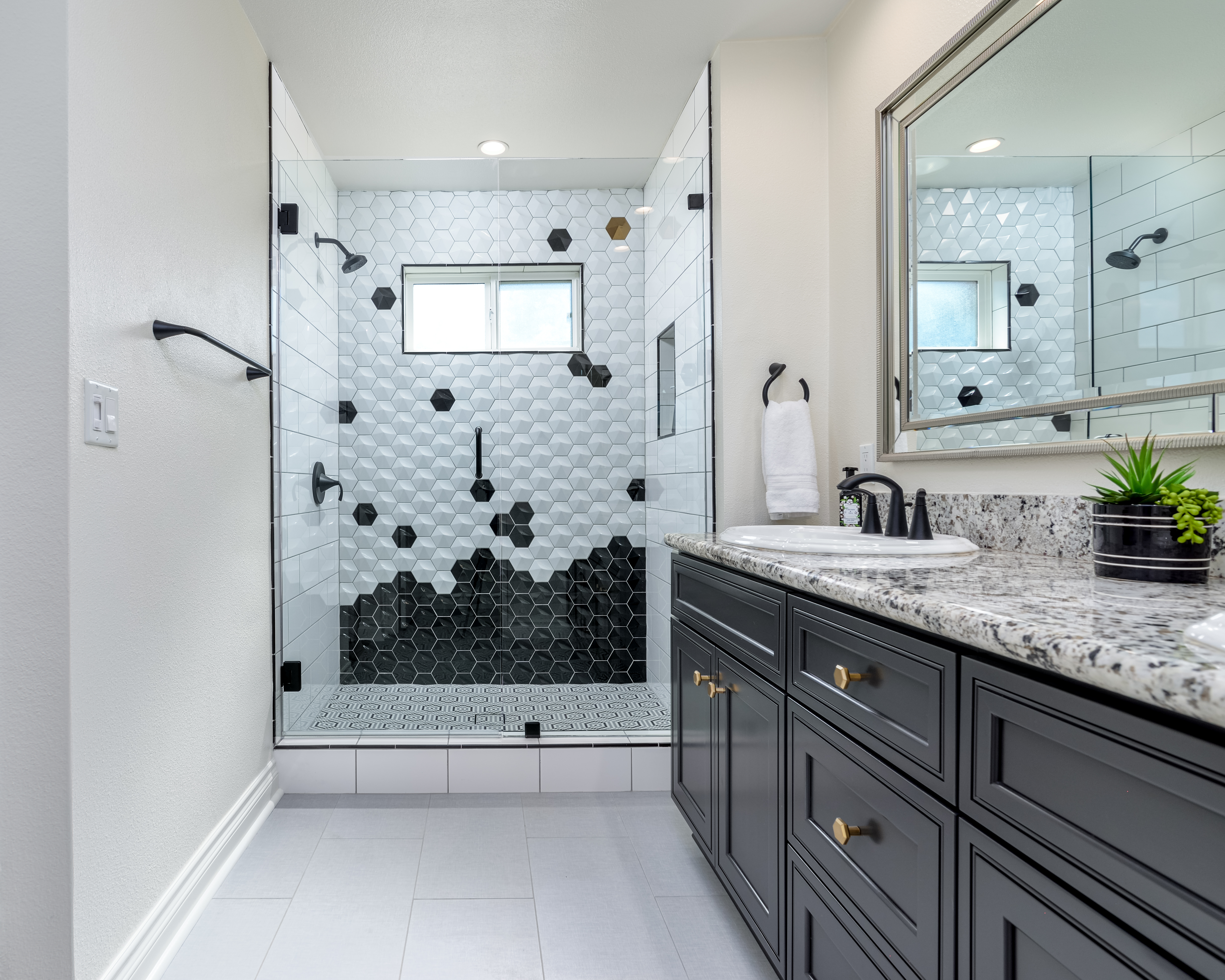 Black and white hex tile shower with dark vanity